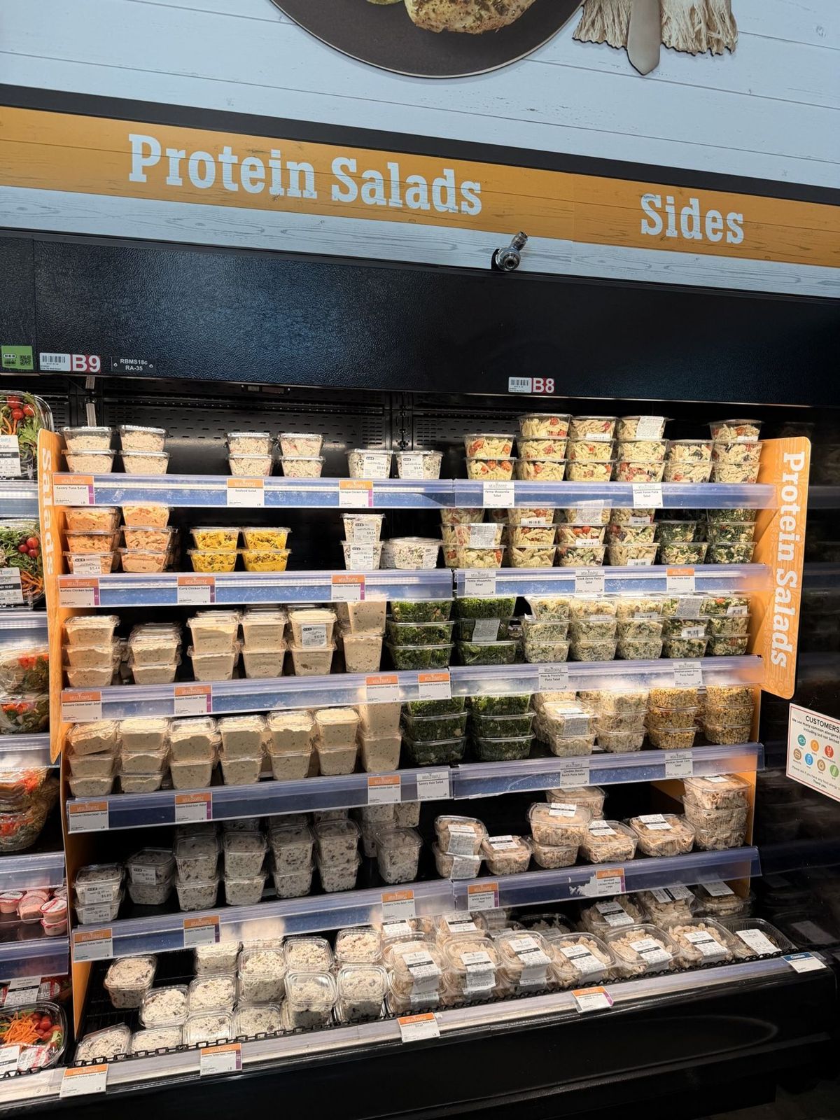H-E-B case of protein salads in tubs under a Protein Salads sign