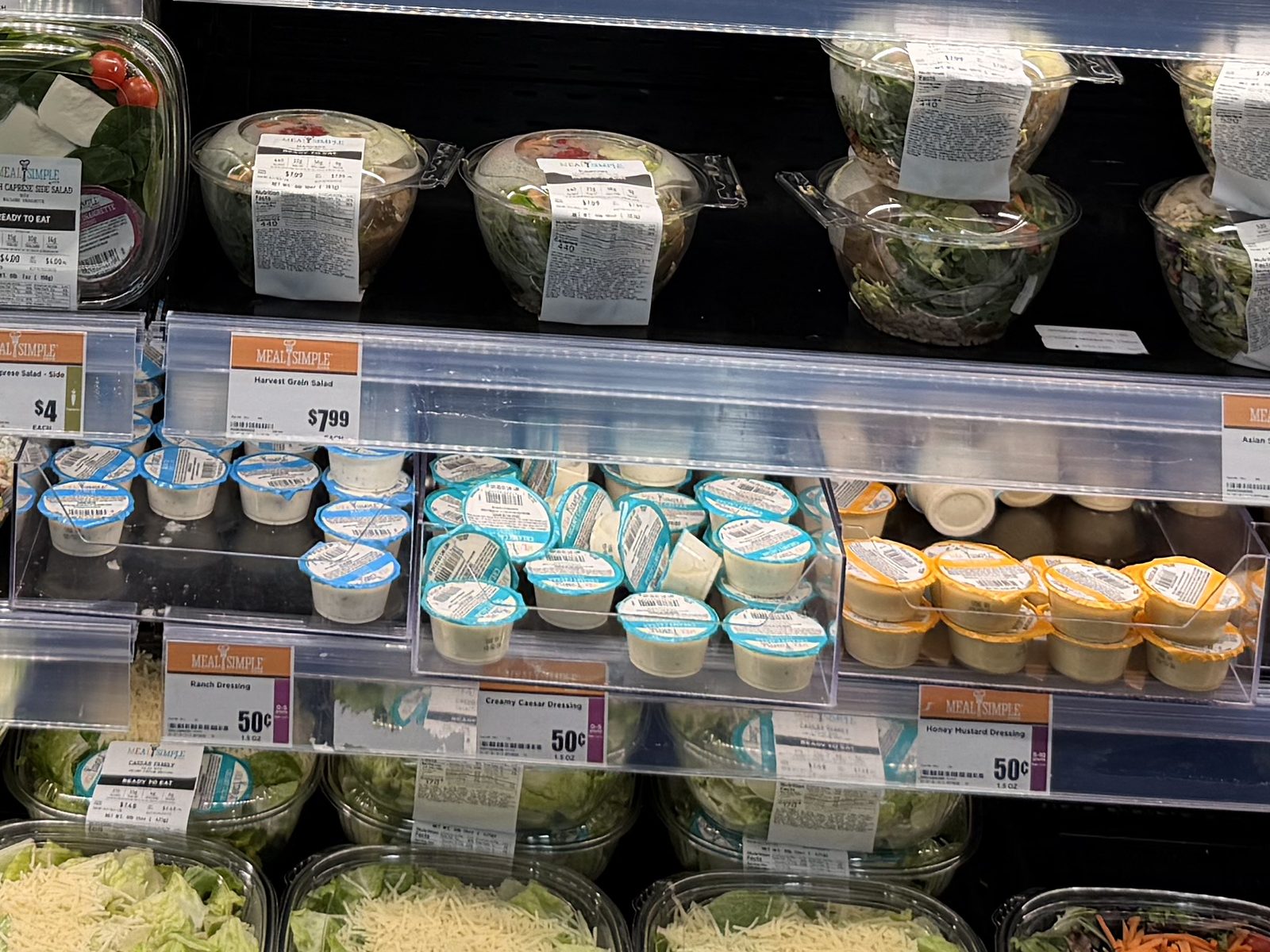 H-E-B dressing cups at 50¢ each, such as ranch, Caesar and honey mustard, below grain salads at $7.99