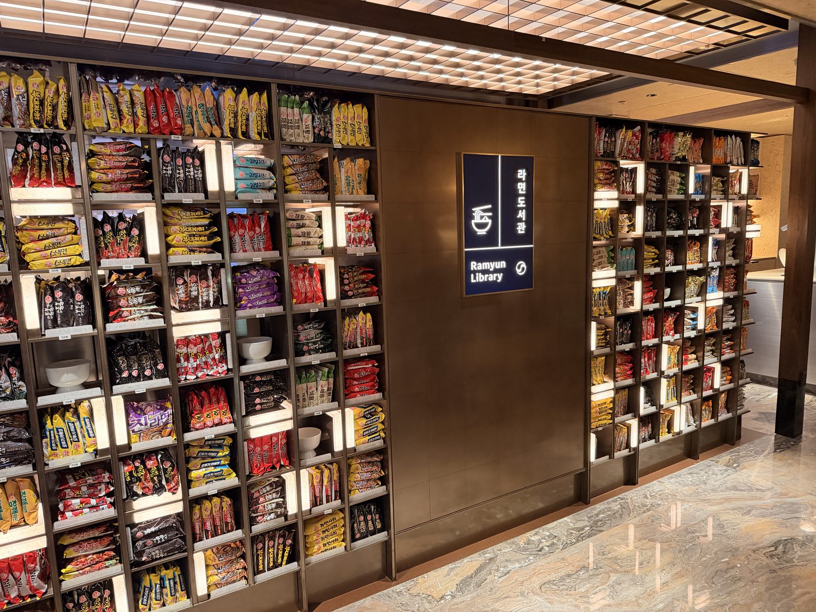 A ramen library of backlit wooden shelves in an airport lounge at Incheon