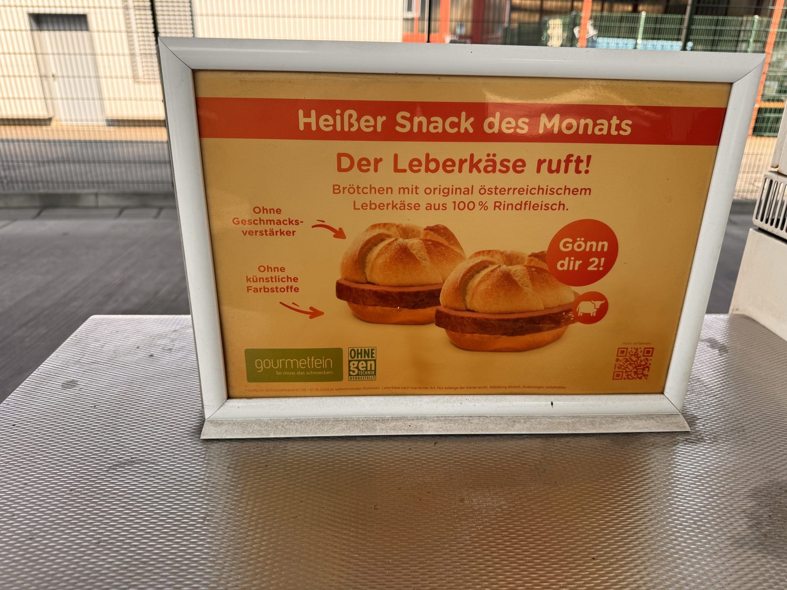 Close-up of the pump island sign: Heißer Snack des Monats, Der Leberkäse ruft!, with 2 Leberkäse rolls